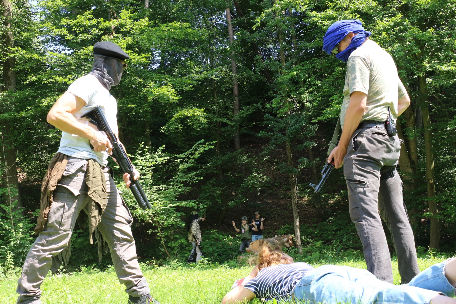 Krisenwerk GmbH - Crisis management training - Two men with mask holding guns on woman lying face‑down on the ground.