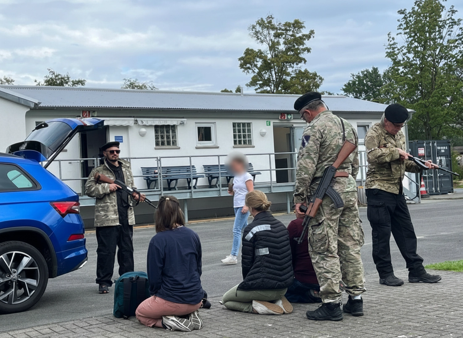 Krisenwerk GmbH - Crisis management training - Three soldiers are standing with guns in hands and three women are kneeled down
